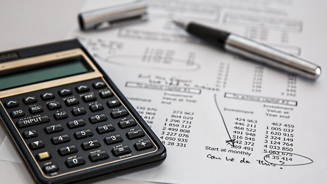 Calculator and pen on budget and investment calculations of cost increase