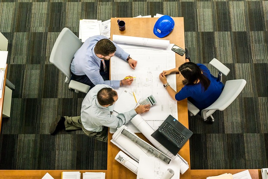 a group of people are sitting around a table looking at plan layout