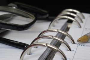 Close up view of a binder planner with glasses, a pen, ehs requirements